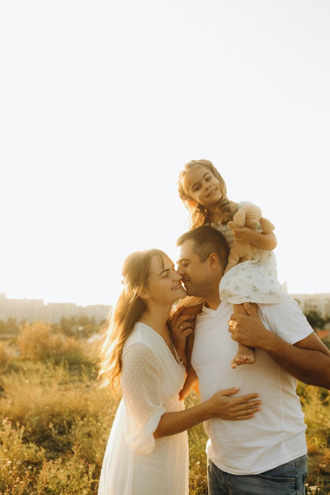 Familj kramas i ett sommarfält i kvällsljus