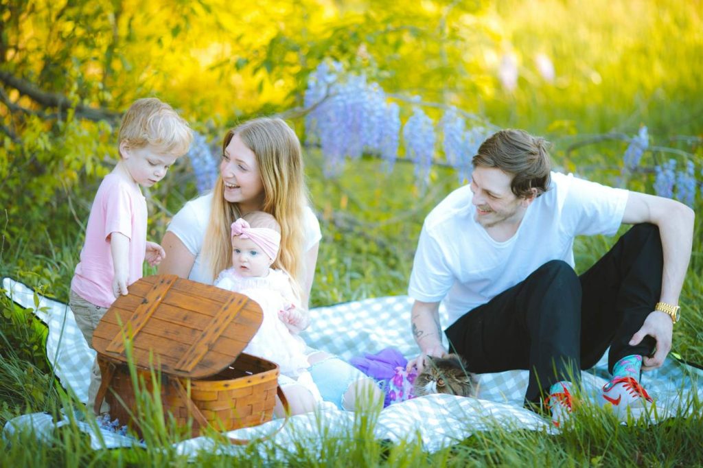 Familj med tre barn har picknick i gräset bland lupiner