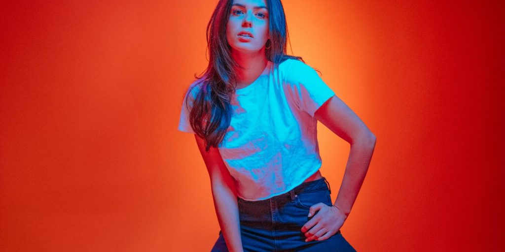 Kvinna i vit t-shirt mot orange och röd färgbakgrund