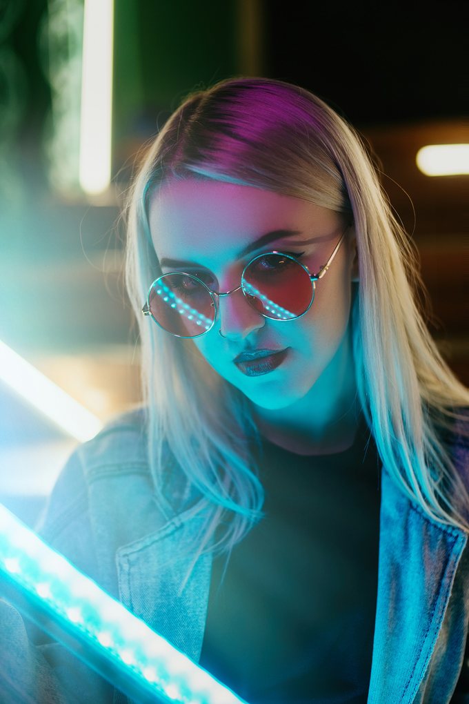 Blond kvinna med solglasögon i blått och rosa neonljus