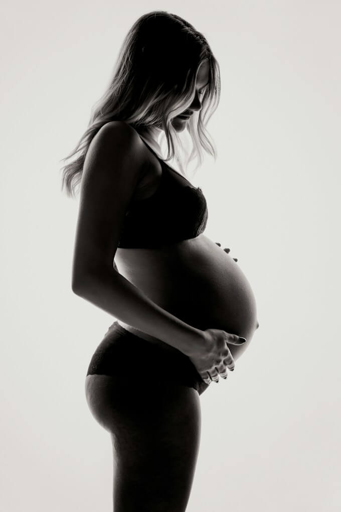 Gravid kvinna i siluett mot vit bakgrund, svartvit stil