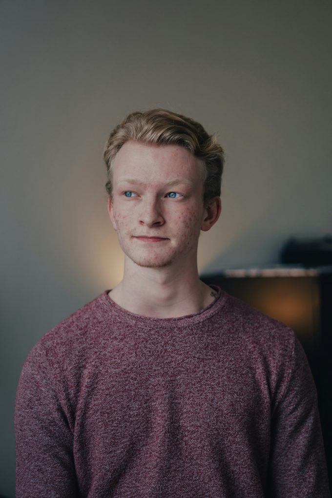 Rödblond ung man i vinröd tröja i naturligt ljus