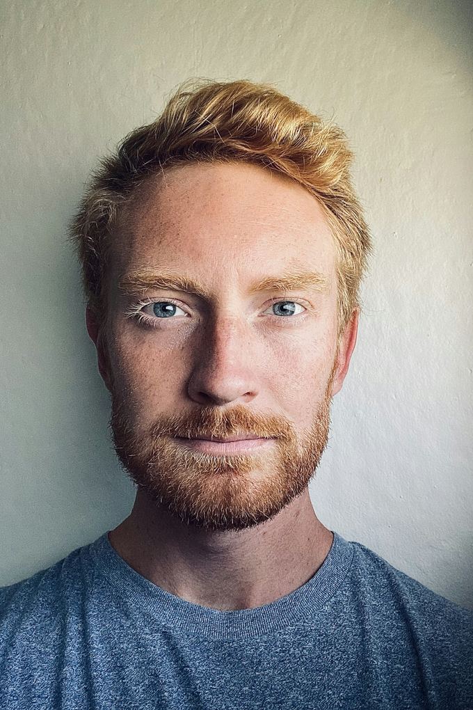 Närbild på rödblond skäggig man med blå ögon och grå t-shirt