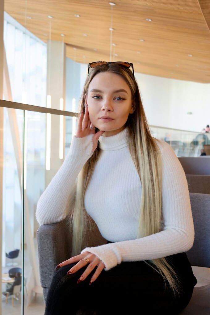 Kvinna i vit polotröja sitter i ljus modern lounge