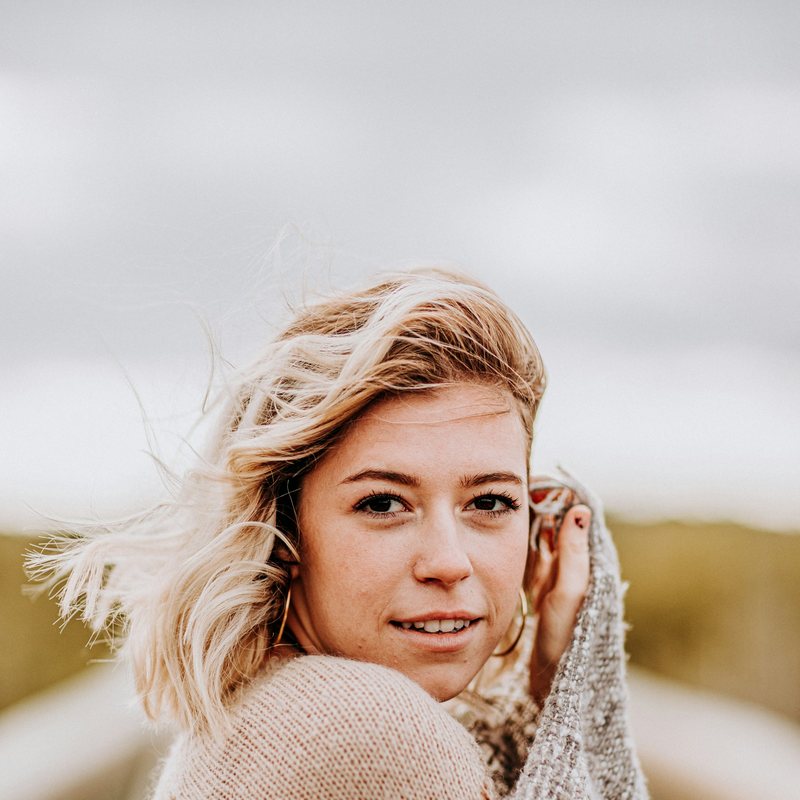 Leende blond kvinna inlindad i en stickad sjal utomhus