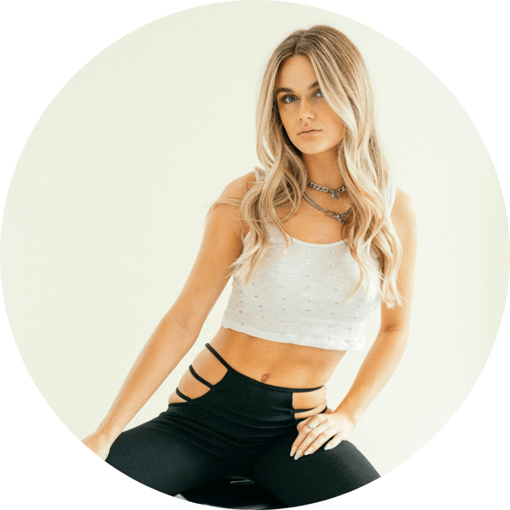 Blond kvinna i vit crop top sitter mot ljus bakgrund, portfolio