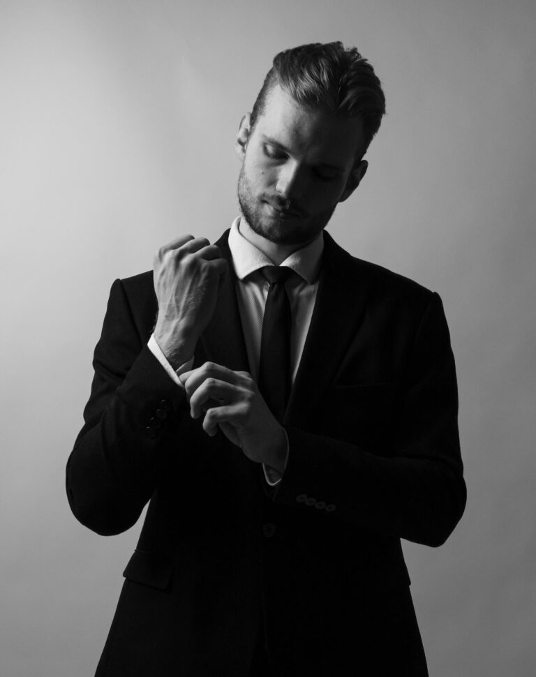 Man i kostym rättar till ärmen i dramatiskt svartvitt ljus, modellfotograf Stockholm