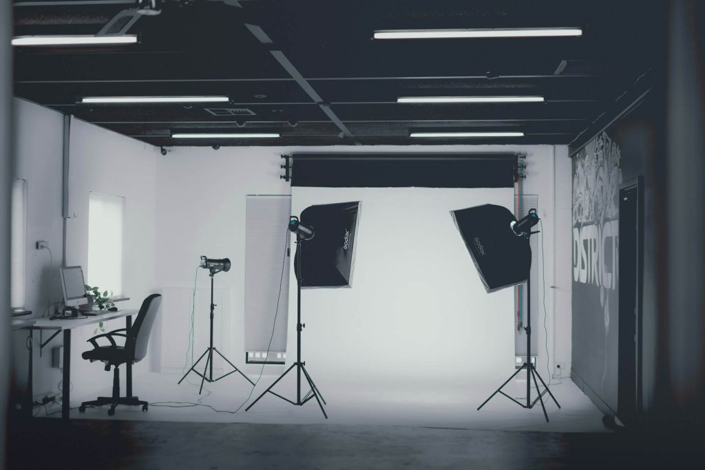 Tom fotostudio med blixtar och softboxar framför vit vägg