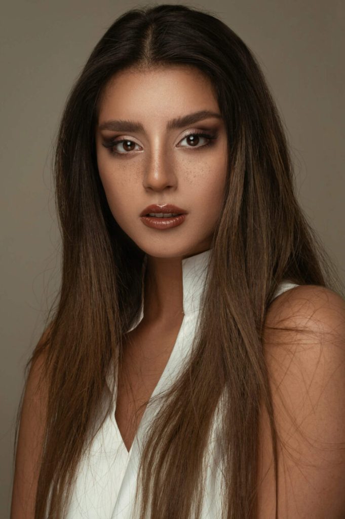 Mörkhårig kvinna med långt hår och dramatisk makeup i studio